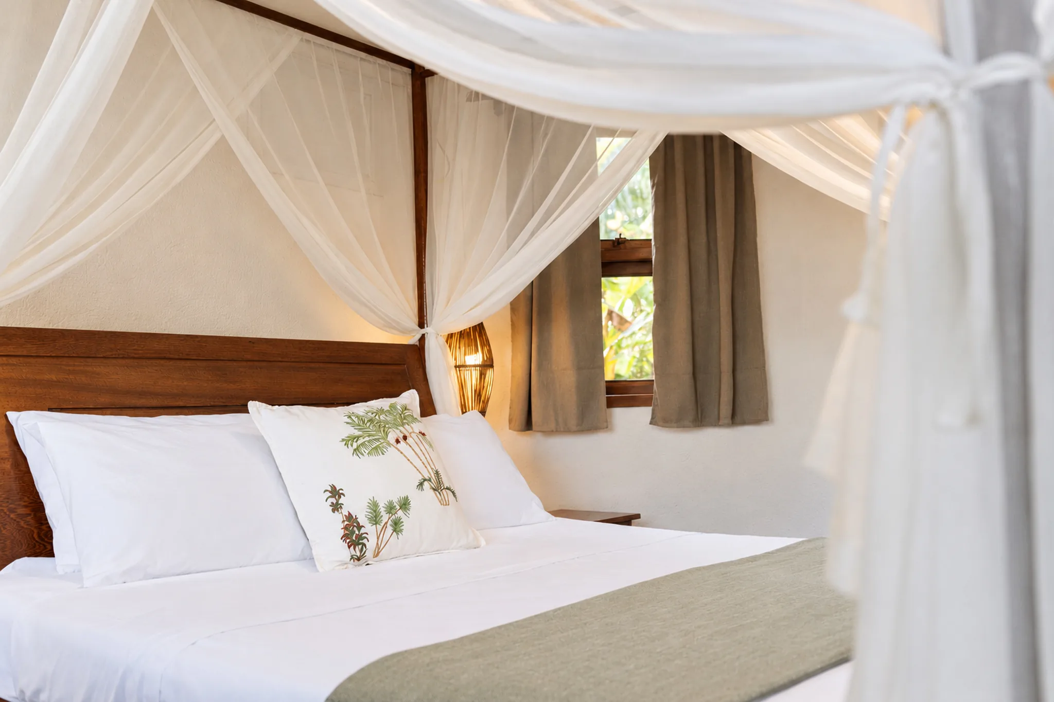 Lit à baldaquin et fenêtre sur le jardin dans la Suite Vue Mer de l’Azorai