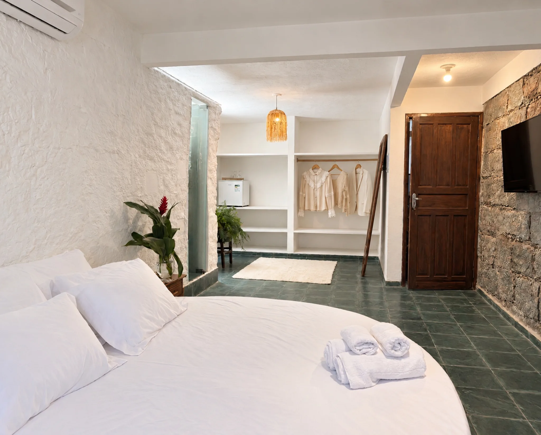 Cama de casal com parede de pedra natural na Suíte Premium do Azorai