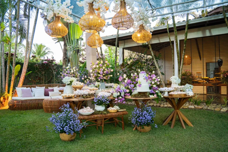 Mesa de doces e flores sob tenda com luminárias de palha no jardim do Azorai
