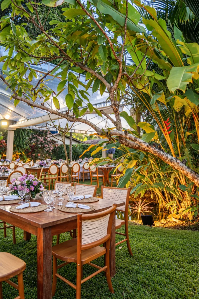 Mesa de madeira posta sob uma árvore no jardim tropical, para recepção de casamento no Azorai