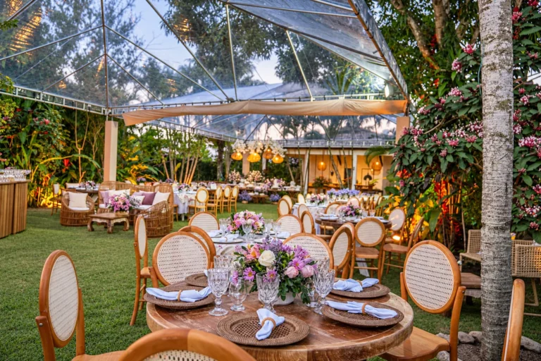 Mesas da recepção de casamento no gramado do jardim tropical do Azorai, ao entardecer