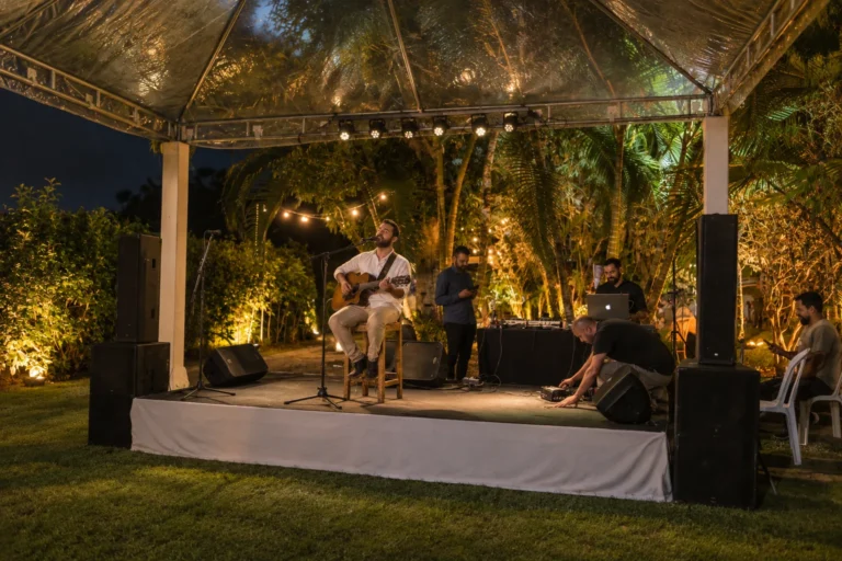 Música ao vivo no palco do jardim tropical, à noite, durante festa de casamento no Azorai